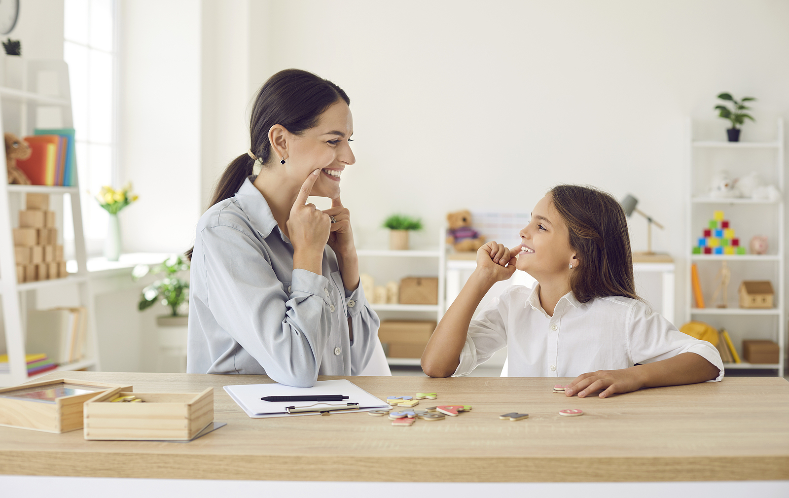 Speech and language therapist helping little child overcome pronunciation problems