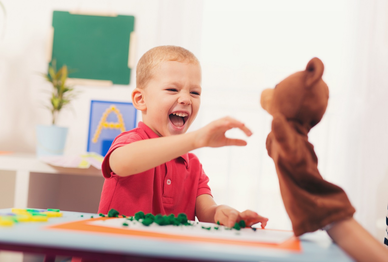 Little boy during lesson with his speech therapist. Learning through fun and play